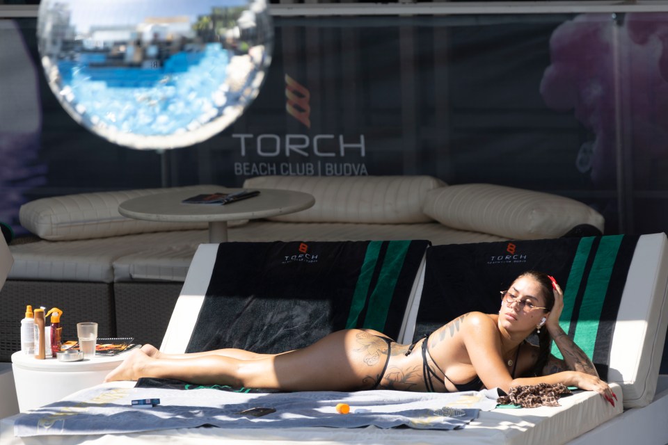 a woman is laying on a lounge chair at torch beach club