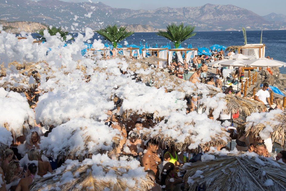a crowd of people on a beach covered in foam