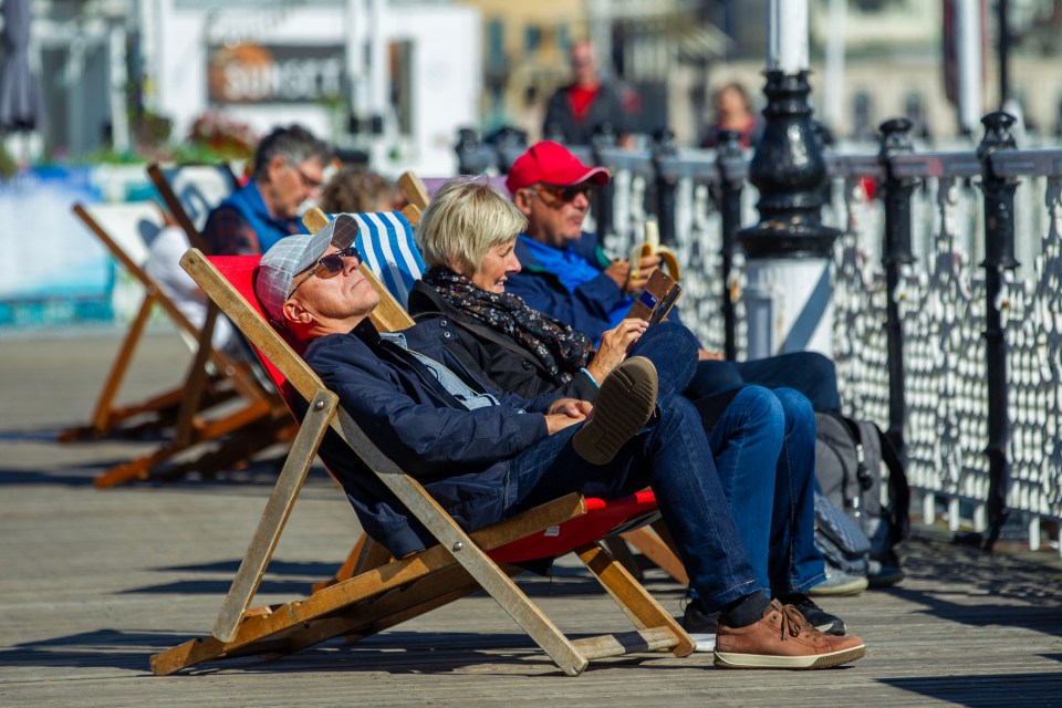a group of people sitting in lawn chairs on a pier with a burger sign in the background