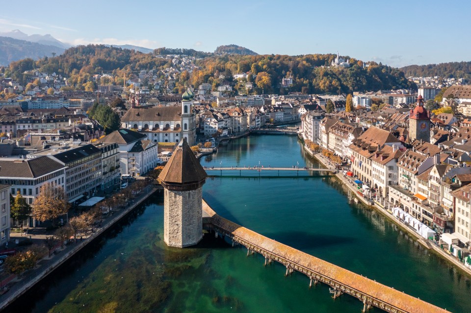 a bridge over a river in a city with mountains in the background