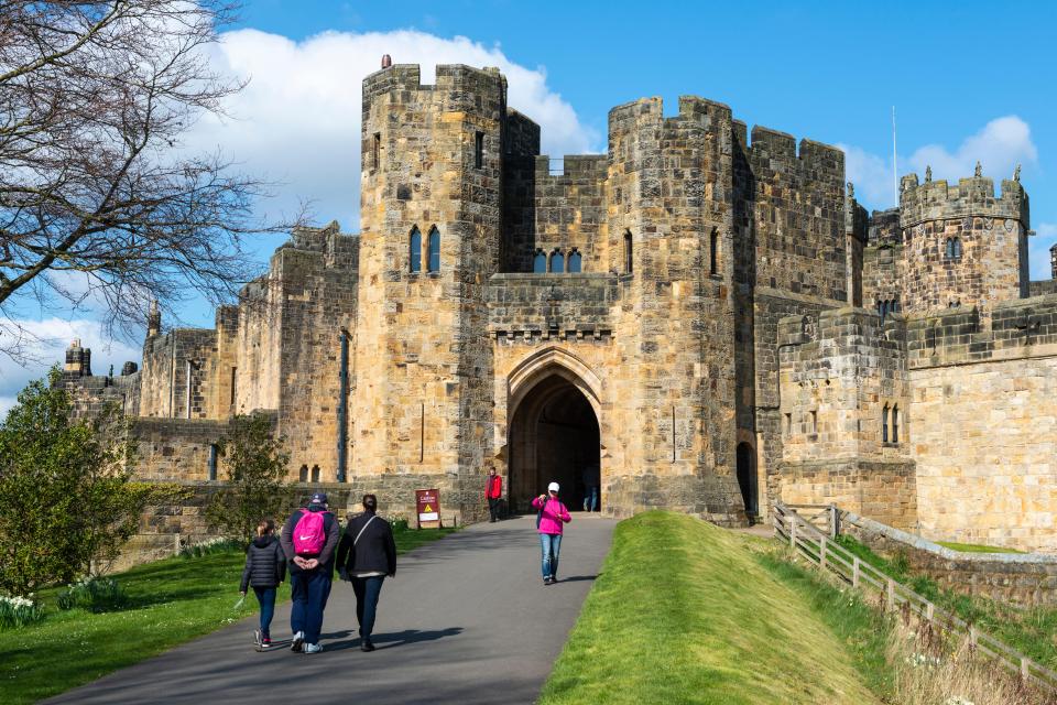 a group of people walking in front of a castle