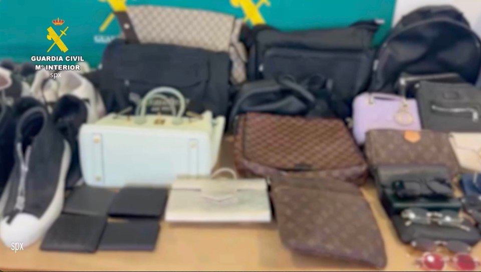 a bunch of handbags are on a table with a guardia civil logo in the background