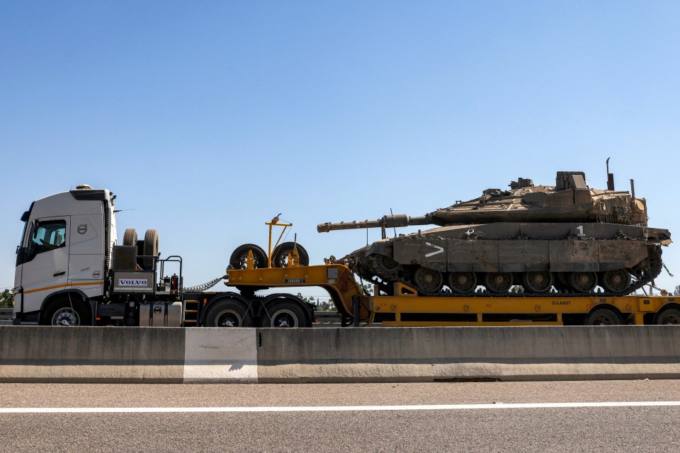 a volvo truck carrying a tank on a highway