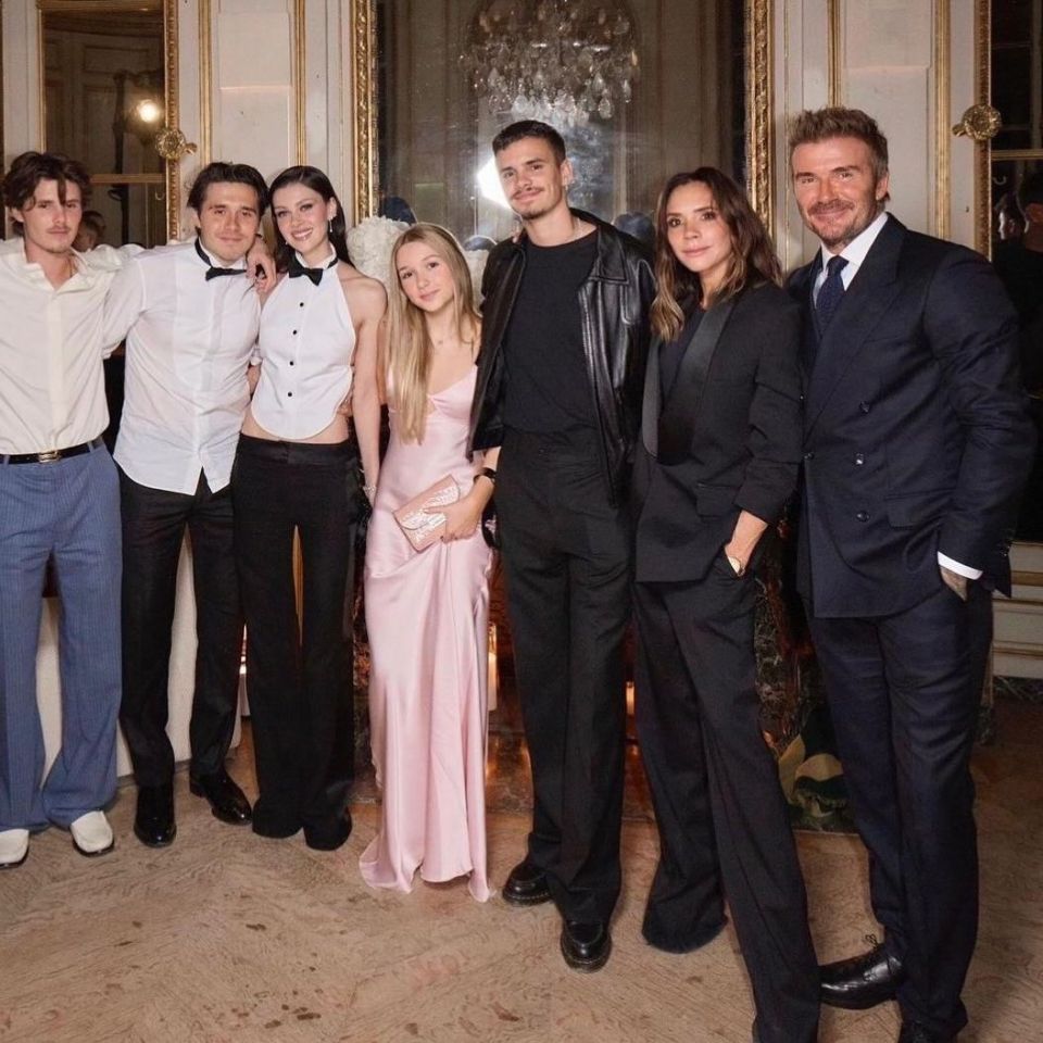 a group of people posing for a picture including a woman in a pink dress