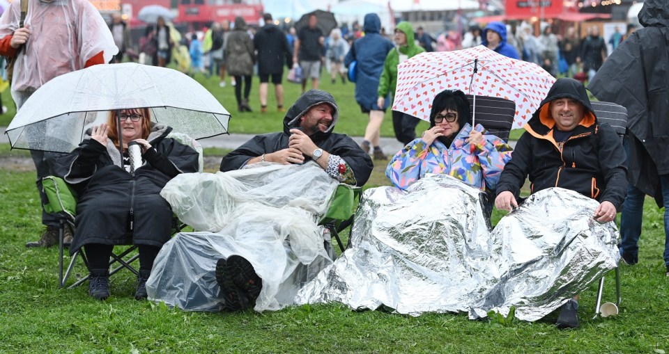 a group of people sitting under umbrellas in the rain