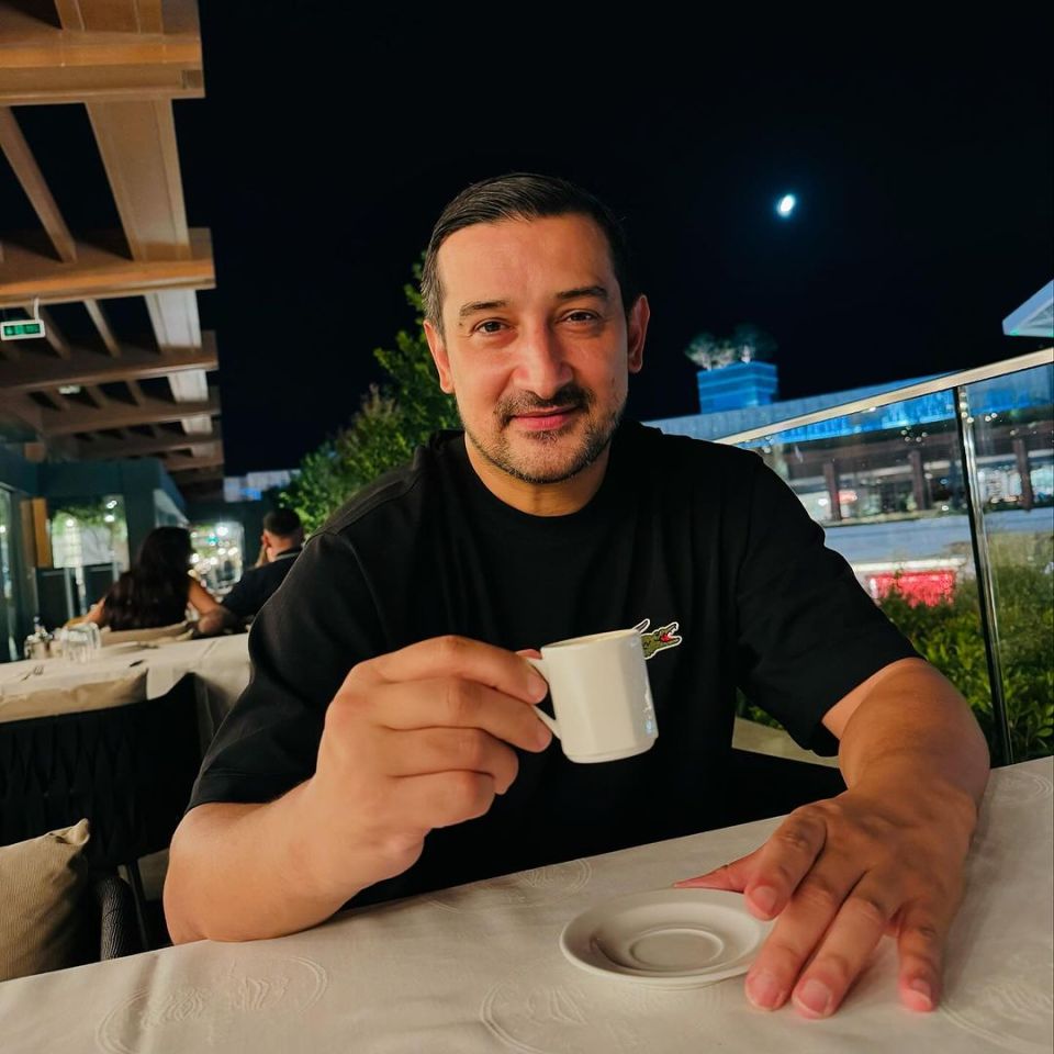 a man sitting at a table holding a cup of coffee