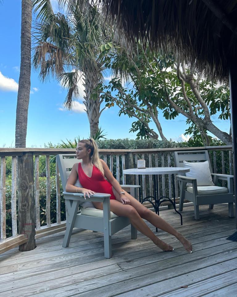 a woman in a red swimsuit sits in a chair on a deck