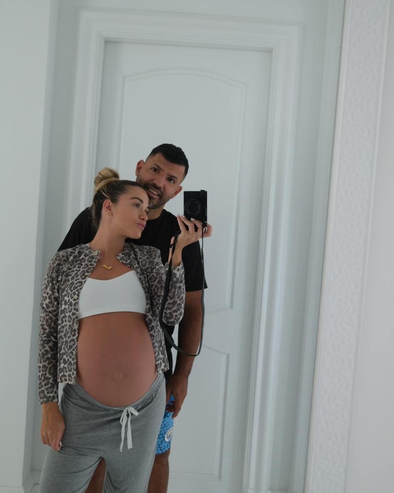 a man and a pregnant woman pose for a picture in front of a mirror