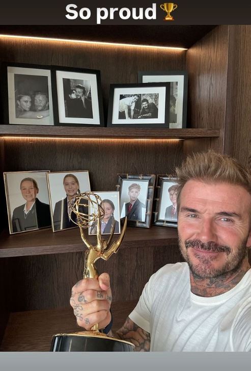 a man is holding a trophy in front of a shelf with pictures on it .