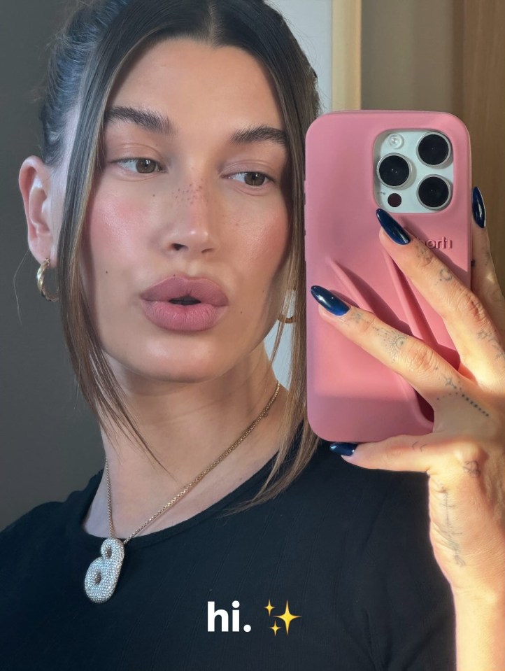 a woman taking a selfie with a pink case that says hi