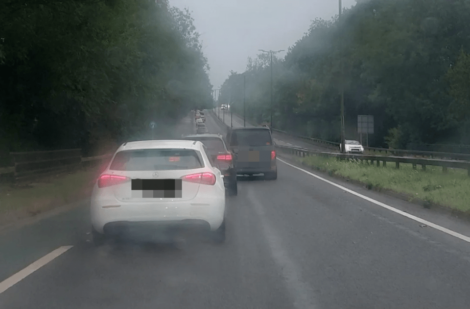 a white mercedes is driving down a foggy road