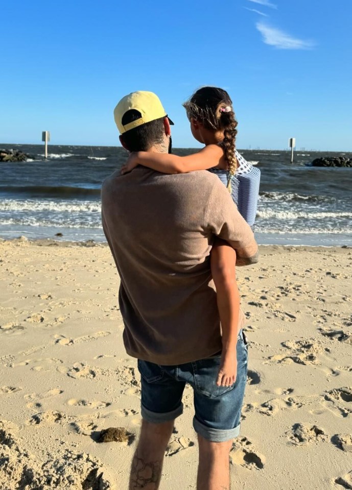 a man is carrying a little girl on his shoulders on the beach