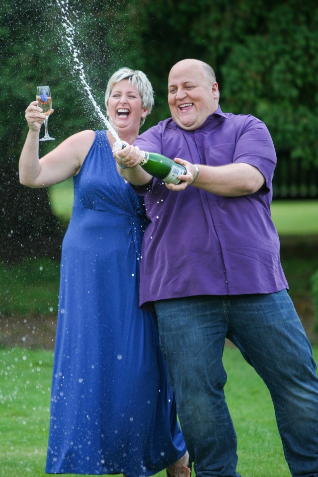 a man and a woman are holding a bottle of champagne
