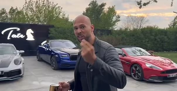 a bald man is standing in front of a row of cars .