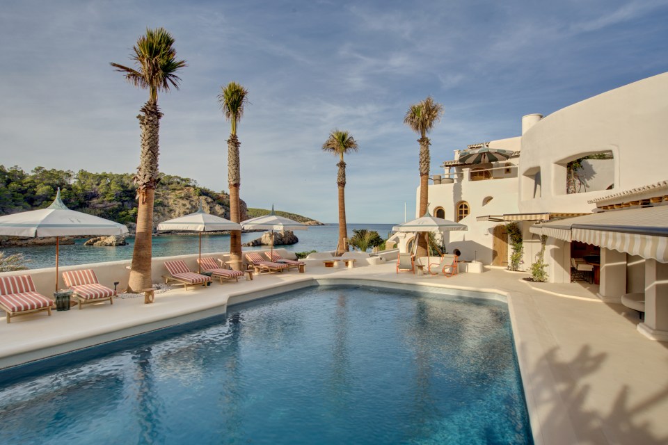 a large swimming pool surrounded by palm trees and chairs