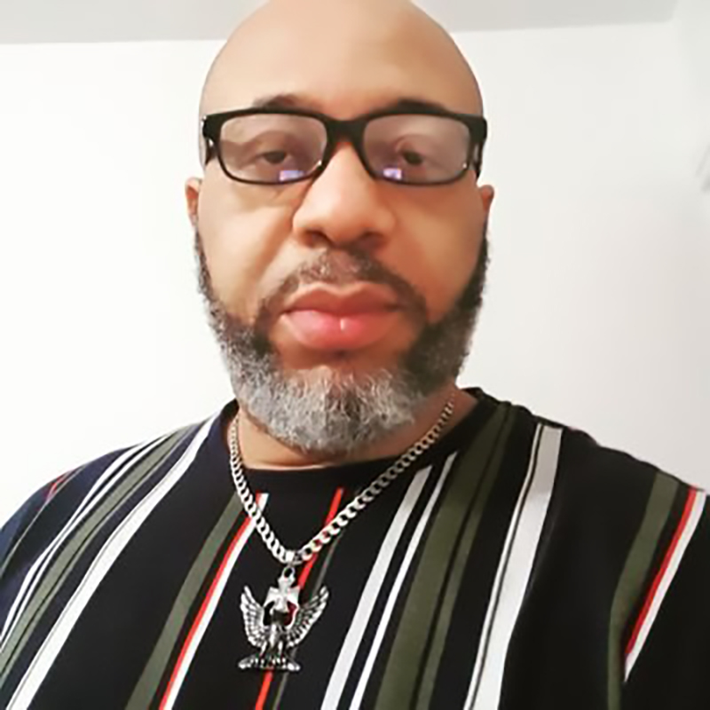 a man wearing glasses and a necklace with an eagle pendant
