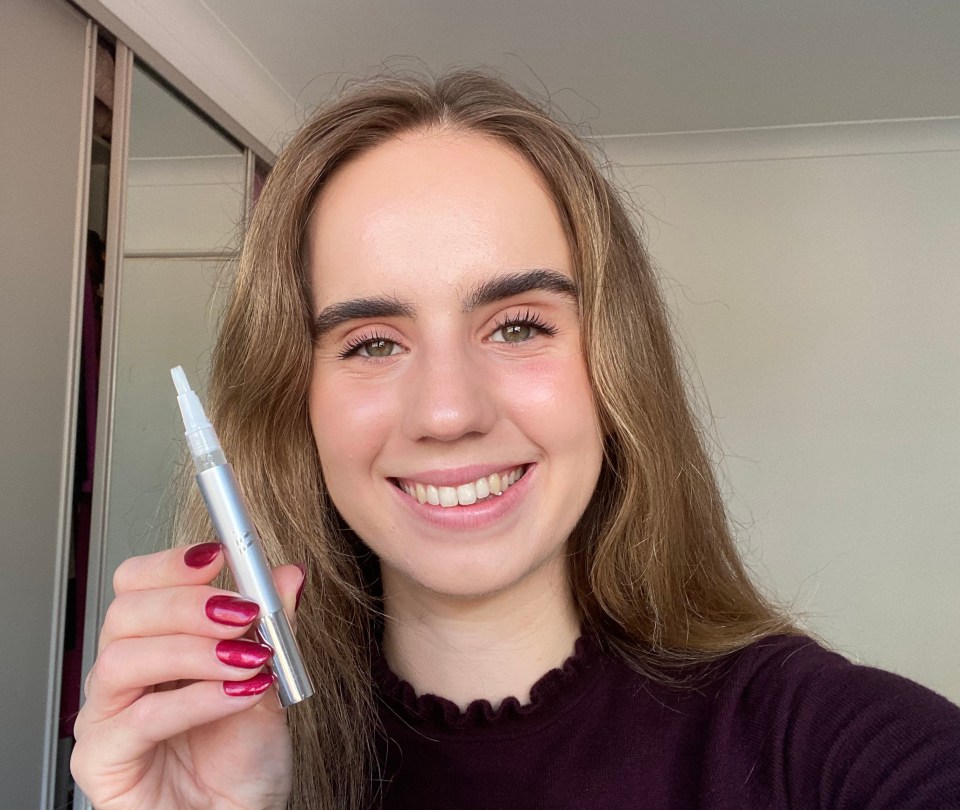 a woman with red nails is holding a whitening pen
