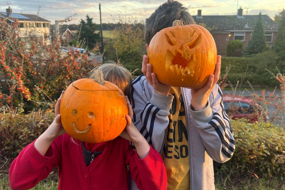 two children holding pumpkins in front of their faces one wearing a jacket that says eso