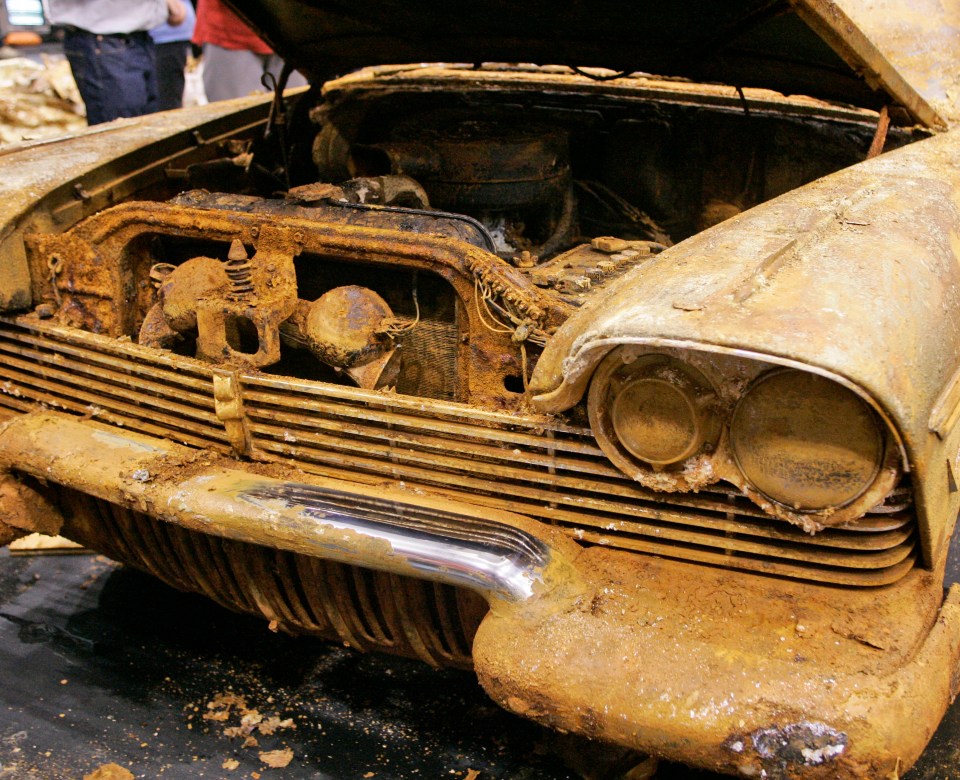 an old rusty car with the hood open