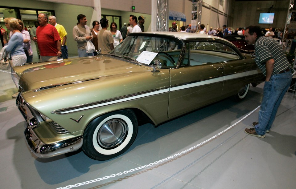 a man is looking at a car with a sign on it that says ' chrysler ' on it