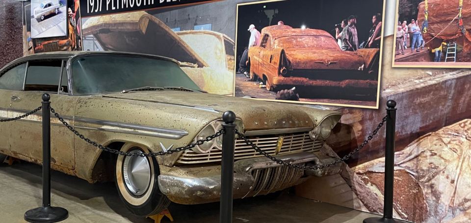 an old plymouth car is behind a chain link fence