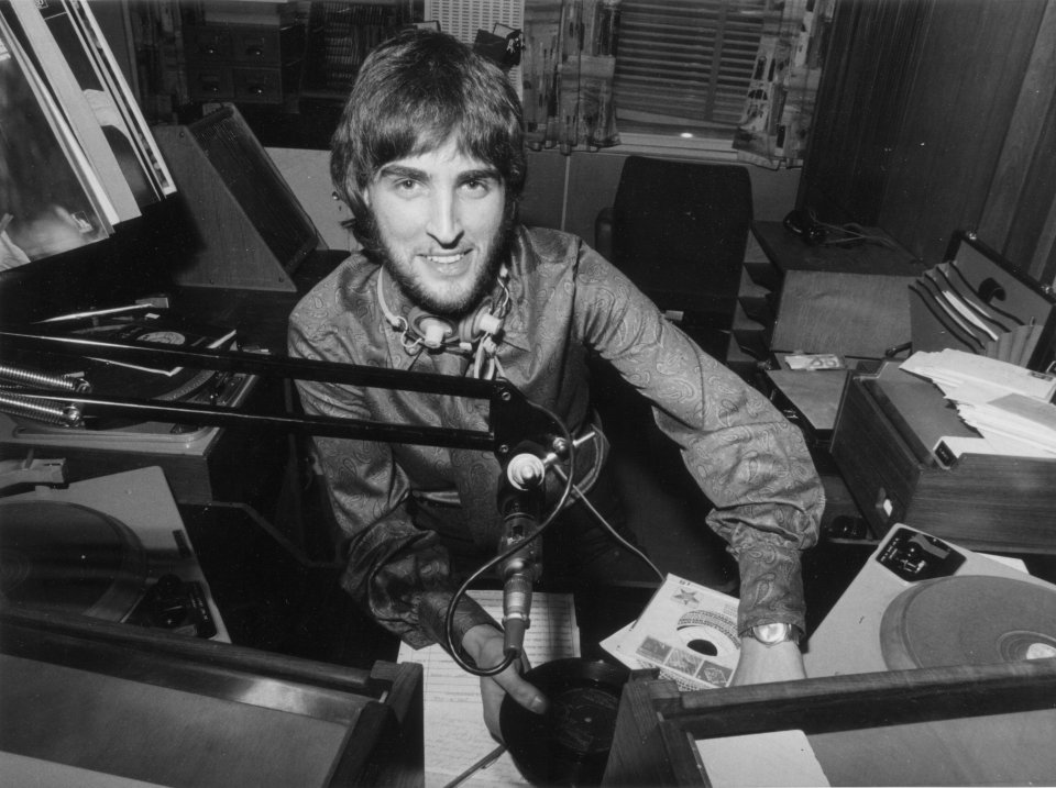 a man sitting in front of a microphone holding a record