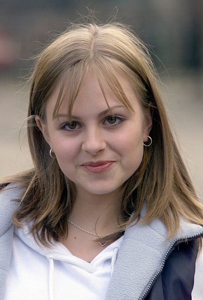 a young woman wearing a white sweatshirt and a blue jacket smiles for the camera