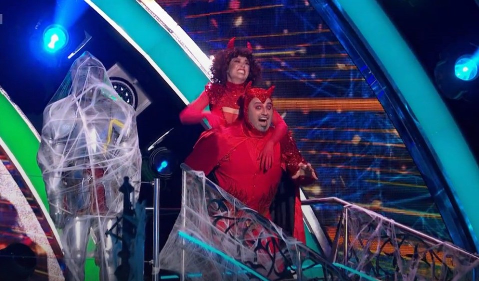 a man in a devil costume is carrying a woman on his shoulders