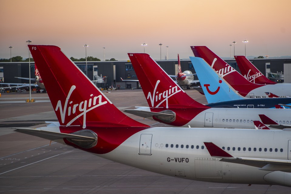 a row of virgin planes are parked on a runway