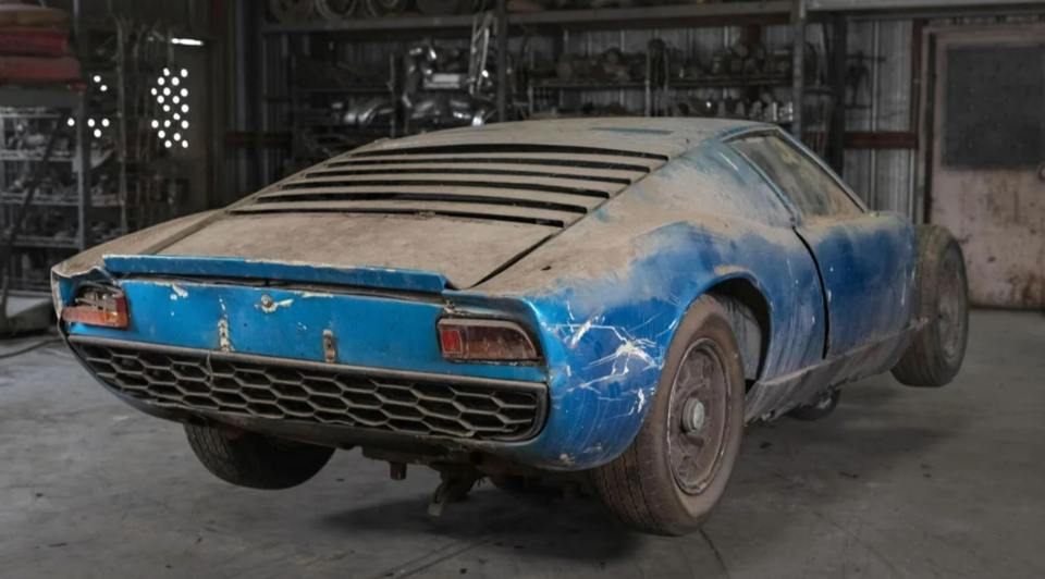a dirty blue car is parked in a garage