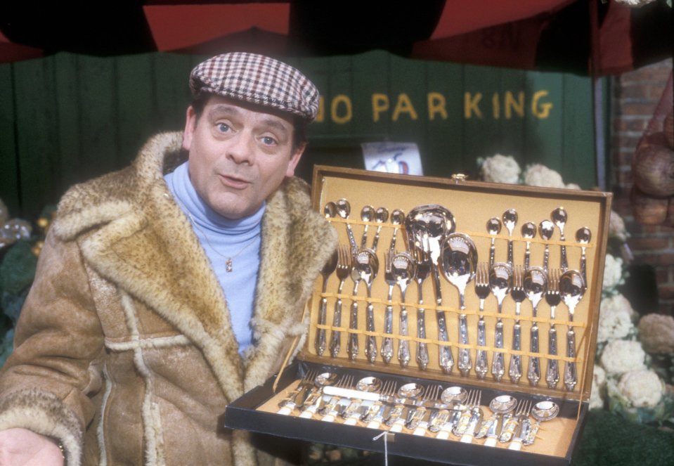 a man holding a box of silverware in front of a no parking sign