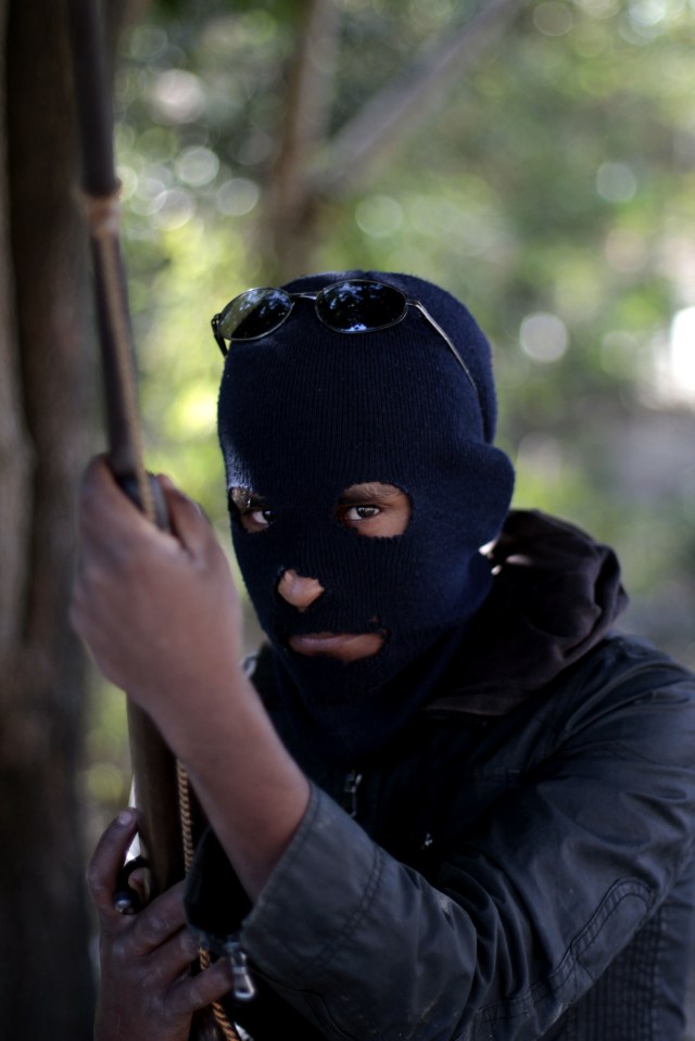 a man wearing a ski mask and sunglasses holds a stick