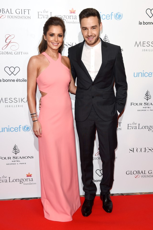 a woman in a pink dress stands next to a man in a black suit
