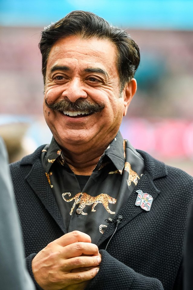 a man with a mustache is smiling and wearing a leopard print shirt