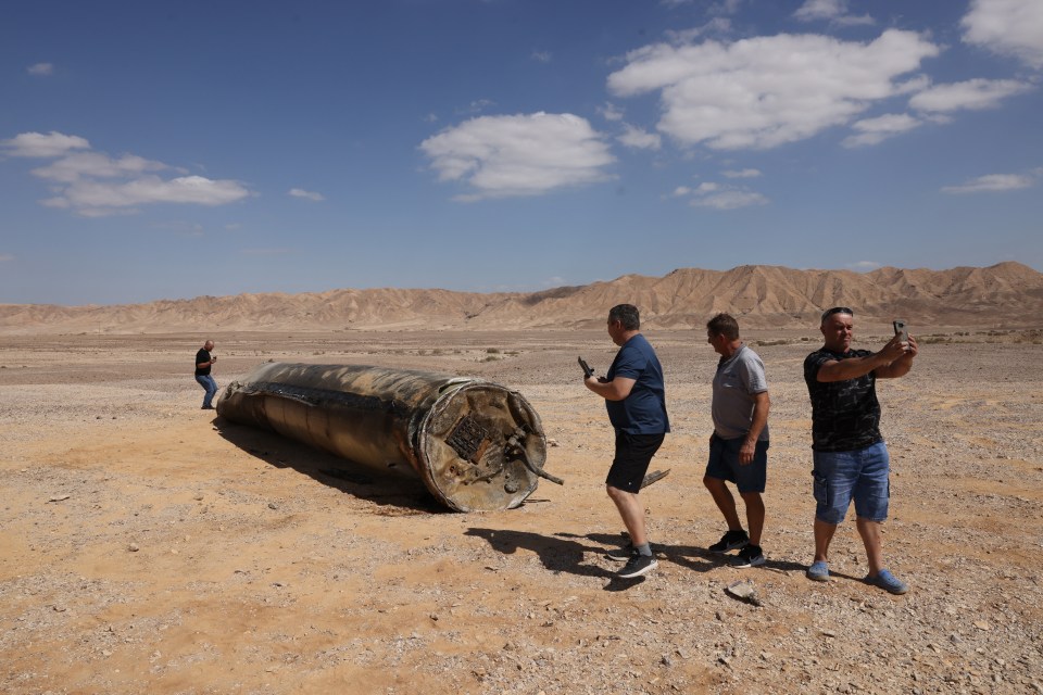 a man taking a picture of a large cylinder in the desert