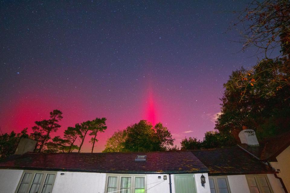 a house with a red light in the sky above it
