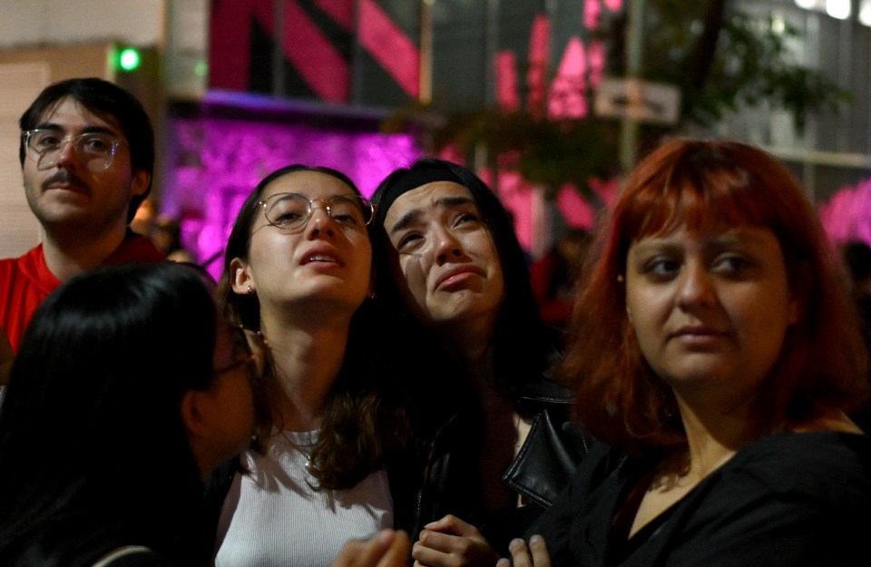 a woman with glasses is crying in a crowd of people