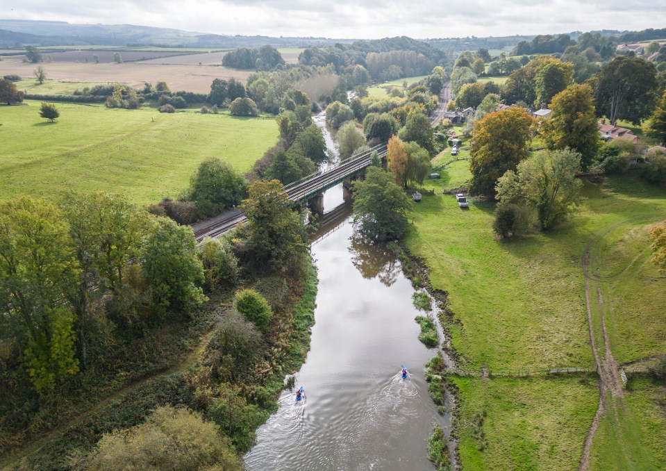 an aerial view of a river with two people in kayaks
