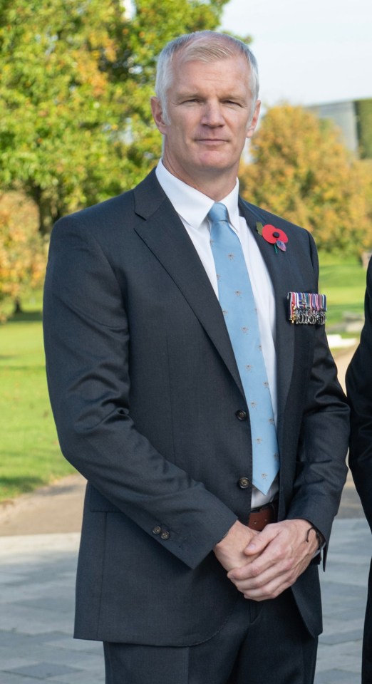 two men are standing next to each other and one has a poppy on his jacket