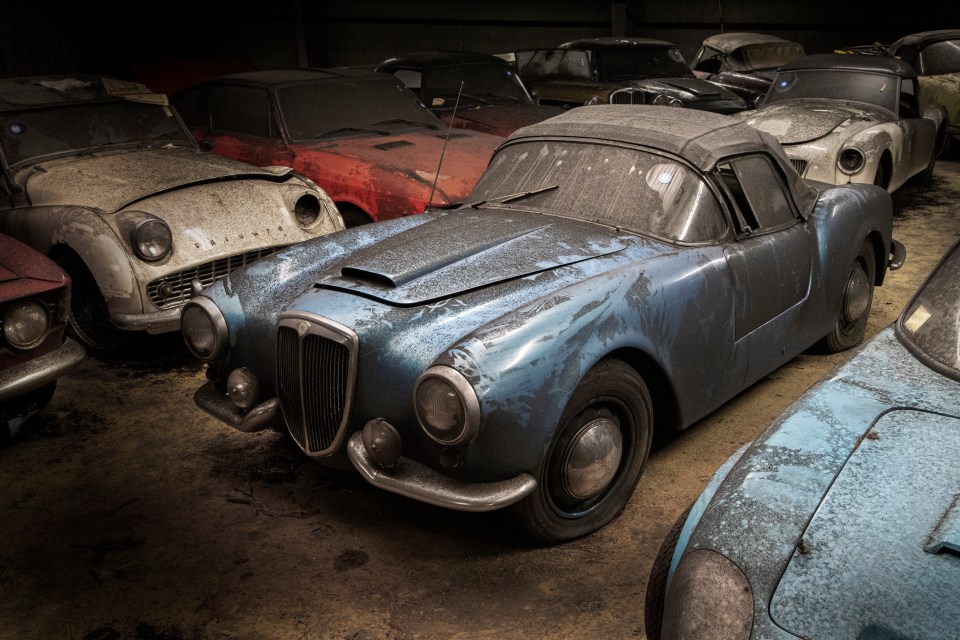 a blue car in a garage with other cars