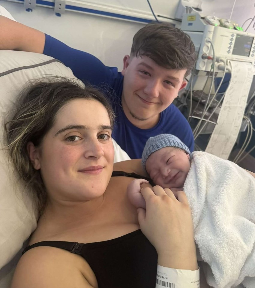 a man and woman hold a newborn baby in front of a sign that says capable and strong