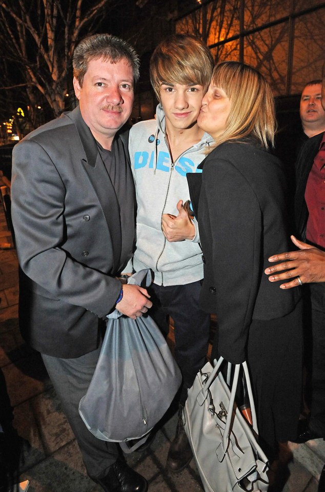a woman kisses a boy on the cheek who is wearing a sweatshirt that says ' dis ' on it