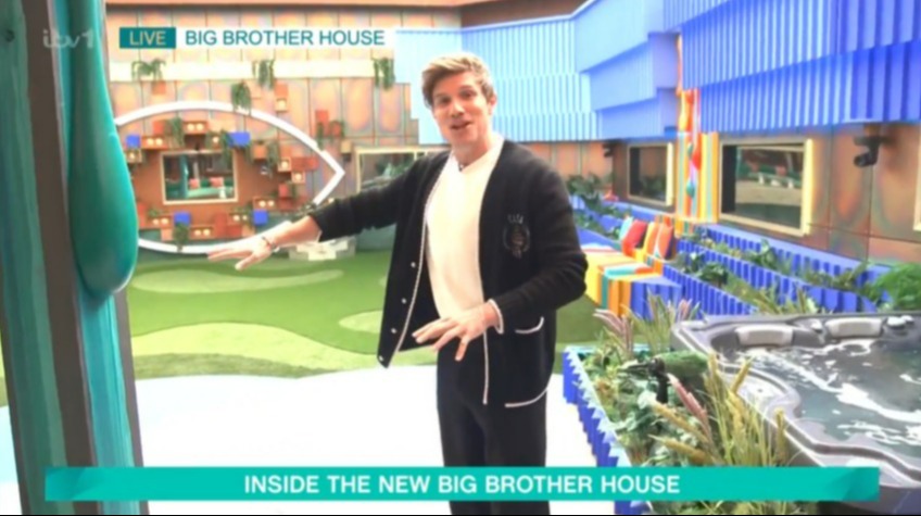 a man is standing in front of a big brother house