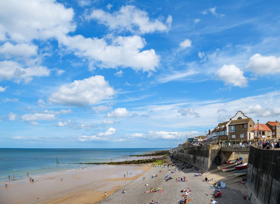a beach scene with a blue sky and white clouds