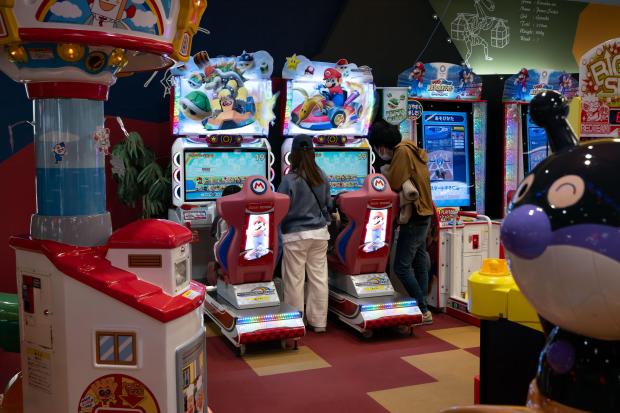 two people are playing mario kart in an arcade