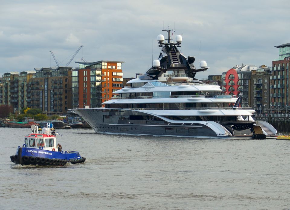a large yacht is being towed by a blue tugboat