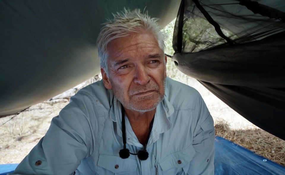 a man in a blue shirt is laying under a tent