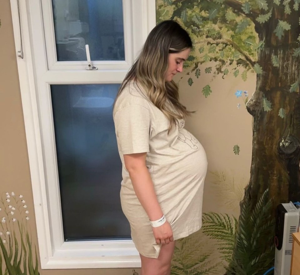 a pregnant woman is standing in front of a window
