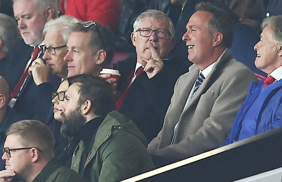 a group of men sit in a stadium with one man covering his mouth with his hand
