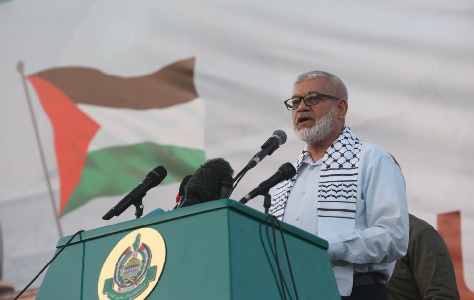 a man stands at a podium with a flag in the background